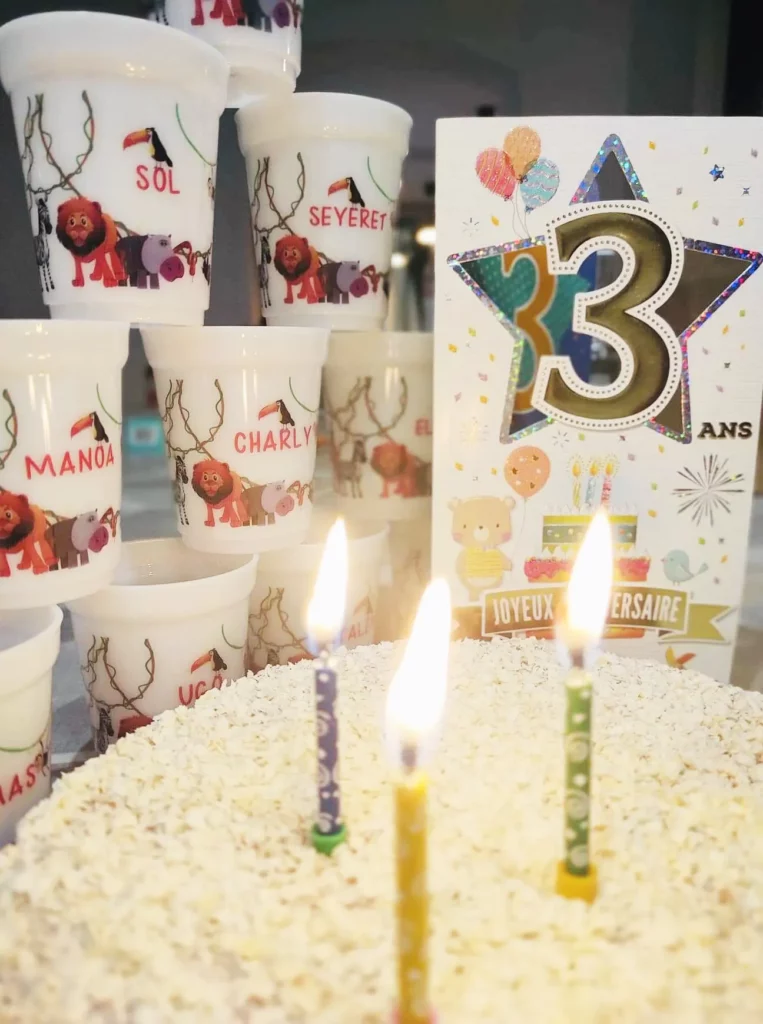 Un gateau d'anniversaire , 3 bougies et des gobelets personnalisés